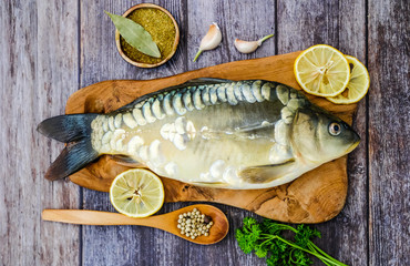Mirror carp on a cutting Board surrounded by vegetables. Fresh fish before cooking. Fish and vegetables.