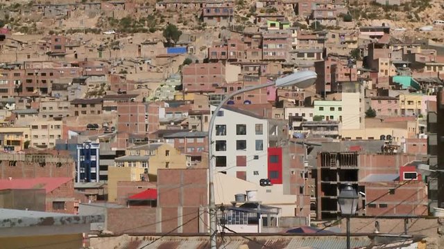 Medium high-angle tilting shot of brown and crowded storey houses on the steep andean hill, Oruro, Bolivia