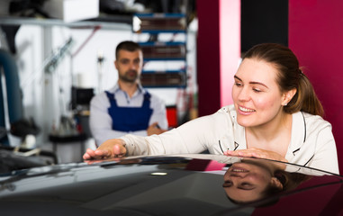 Happy woman touching surface of repainted car