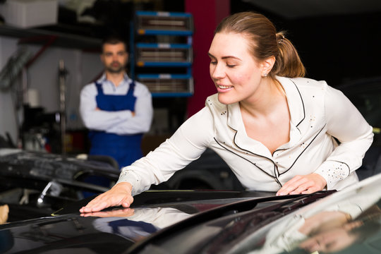 Happy woman touching surface of repainted car