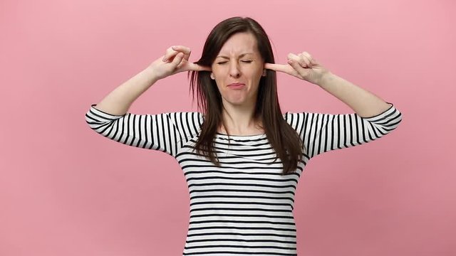 Irritated dissatisfied brunette young woman in striped shirt looking camera gesticulating say no bla-bla-bla isolated over pastel pink background in studio. People sincere emotions, lifestyle concept.