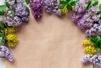 Border of various lilac flowers on craft paper background