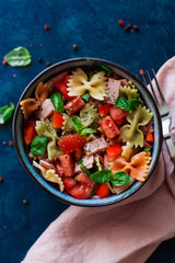 Italian salad with pasta ham and vegetables blue background