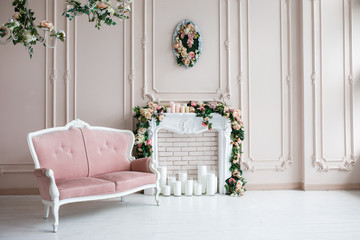 Elegant white fireplace full of flowers. Elegant white room with a sofa. Wedding area. Vintage decor in a bright interior