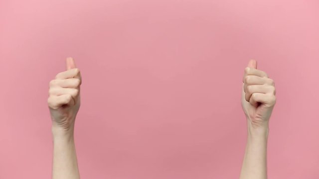 Woman hands pointing on copyspace, showing thumbs up ok gesture isolated over pastel pink background in studio. Copy space for advertisement. With place for text or image. Advertising area, mock up.