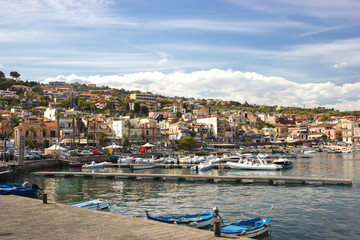 Fototapeta na wymiar Acitrezza Sicily, view of the tourist harbor, fishing boats, houses of the town and blue sky