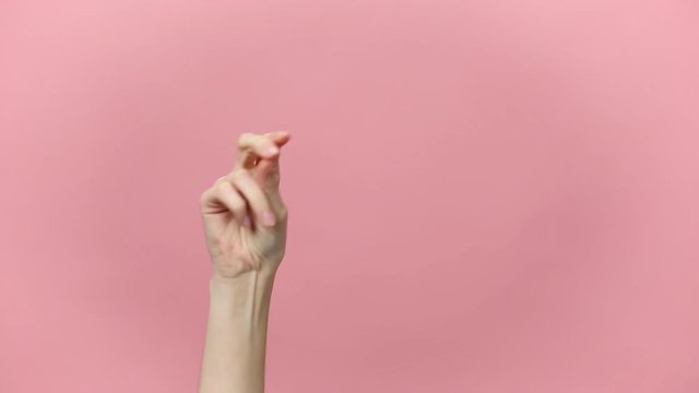 Woman hand snaps her fingers to rhythm, showing thumbs up gesture isolated over pastel pink background in studio. Copy space for advertisement. With place for text or image. Advertising area, mock up.