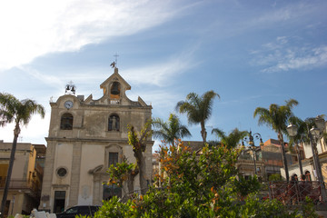 Fototapeta na wymiar Acitrezza Sicily, beautiful church of the town in a square in front of the harbor, blue sunny sky