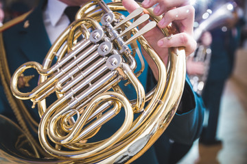 French horn on a wooden table. Beautiful polished musical instrument. Dark background.