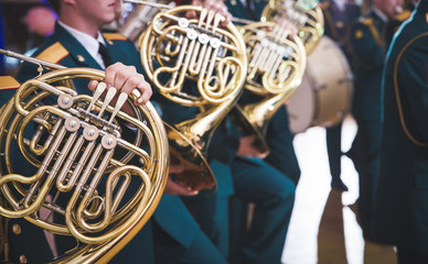 French horn and child hands. Musical brass instruments, adults and children. Concert in the school.