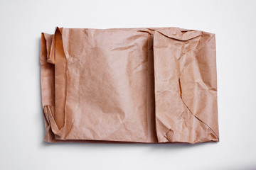 Old empty brown craft package on white background. Delivery pouch. Crumpled paper texture.