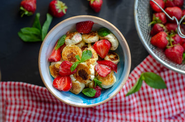 mini cheese pancakes with honey and strawberries on black background. proper nutrition healthy dessert