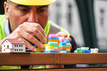 Concentrated civil engineer using multicoloured plastic construction toy building blocks. Outdoors