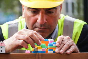 Concentrated civil engineer using multicoloured plastic construction toy building blocks. Outdoors