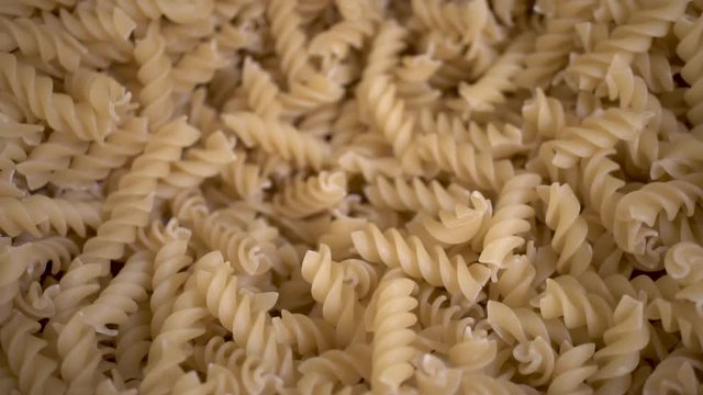 Uncooked spiral rotini noodles in bulk, Isolated Close Up Background