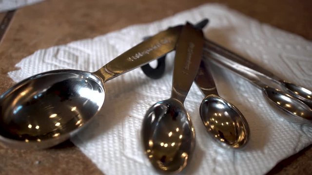 Stainless steel measuring spoons on paper towel, Close Up Slider