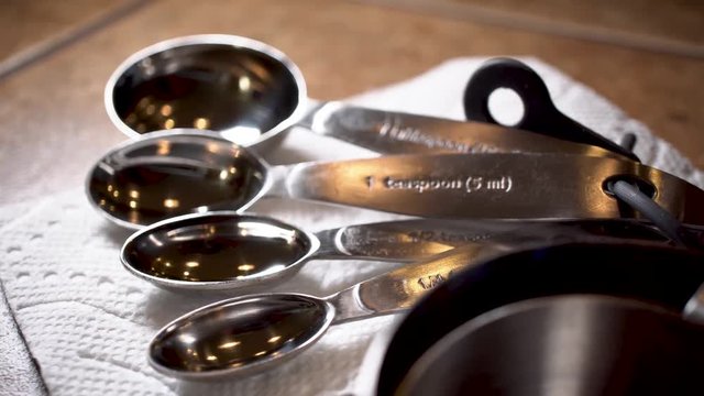 Metal measuring spoons and cups on napkin on counter, Close Up Slider