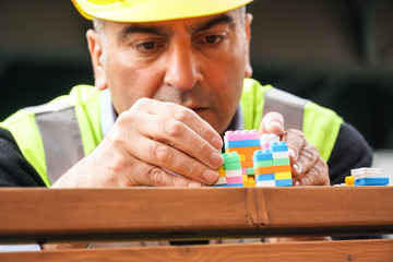 Concentrated civil engineer using multicoloured plastic construction toy building blocks. Outdoors