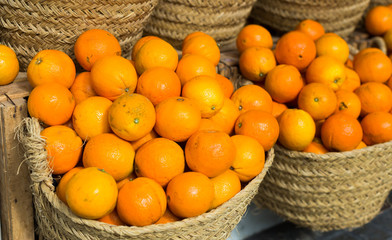 pile of juicy oranges in wicker baskets on market counter