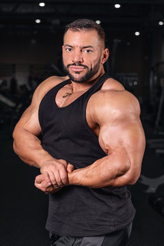 biceps. young man lifting weights in gym. barbell. Bodybuilder in the gym. Sports photo shoot. Man's fitness. Training and exercises with dumbbells. Men's photo shoot in low key. Athletic build. weigh