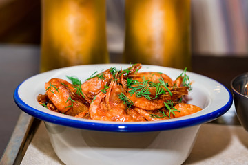 Prepared shrimps with dill in bowl on table with two beer glasses