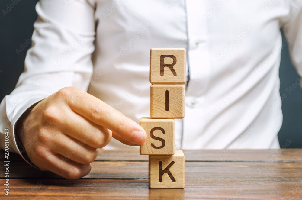 Wall mural man removes blocks with the word risk. the concept of reducing possible risks. insurance, stability 