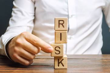 Man removes blocks with the word Risk. The concept of reducing possible risks. Insurance, stability...