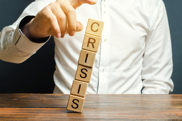 Businessman removes wooden blocks with the word Crisis. The exit from the crisis and financial...