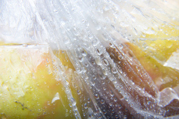 Bolsa de plástico en la cual hay dos manzanas, la bolsa está llena de gotas de agua