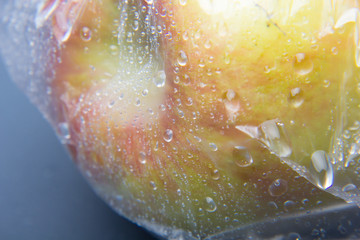 Bolsa de plástico en la cual hay dos manzanas, la bolsa está llena de gotas de agua
