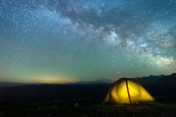 tourist tent of yellow color against the night sky with the Milky Way