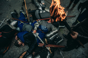 The murdered medieval knights lie on the battlefield next to the standing winners.