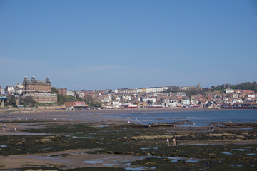 View across beach at low tide  towards Scarborough town and castle on hill, under a clear blue sky on a sunny day 