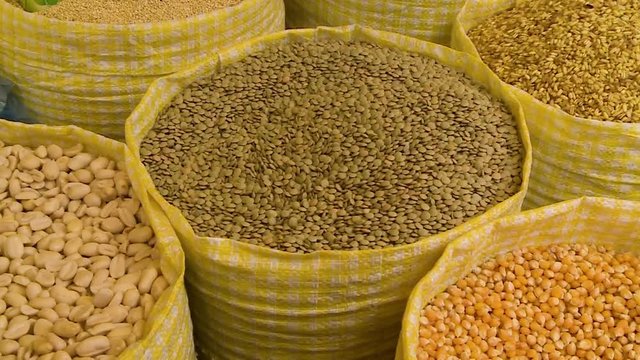 High-angle close-up panning, tilting, and zooming shot of fresh grains in bags at a market, Oruro, Bolivia