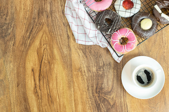 Donuts and coffee on wooden table, top view
