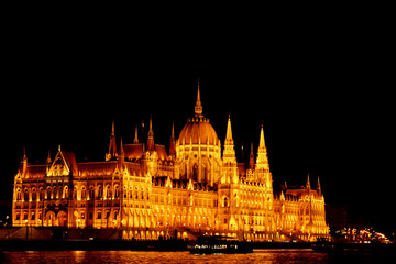 Fototapeta premium Budapest Hungary, 05.29.2019 Hungarian Parliament Building on the banks of the Danube River. night Budapest, glowing in gold. facade and roof of an old building