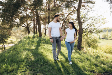 Happy young couple expecting baby in summer park