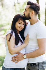 Obraz premium Pregnant woman and her beaeded husband hugging on the tummy together in nature outdoor