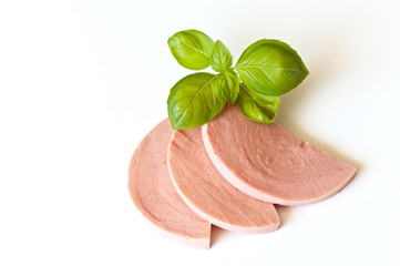 Three delicious pieces of boiled sausage with an aromatic sprig of green basil on a white background. Close-up, place for text