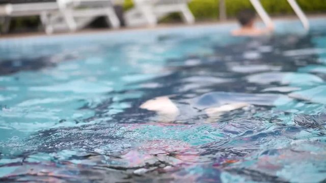Asian girl swimming in swimming pool, slow motion.