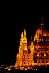 Fototapeta premium Budapest Hungary, 05.29.2019 Hungarian Parliament Building on the banks of the Danube River. night Budapest, glowing in gold. facade and roof of an old building