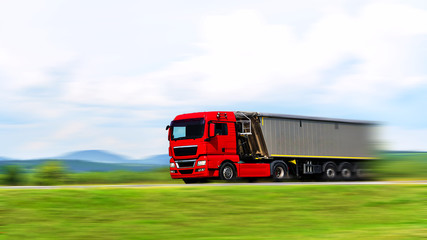 Modern red generic truck with load moving fast on the highway - motion blur effect (copy space)