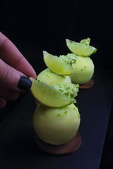 Green lime desserts on chocolate cookie with hand putting a fresh lime slice
