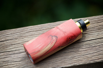 high end red and natural stabilized wood box mods with rebuildable dripping atomizer on natural wood texture background, vaporizer equipment, selective focus