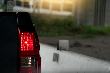 Close up light break of pickup car black color beside road with concrete.