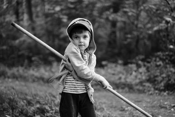 Little boy playing with a stick in the forest