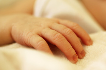 Obraz na płótnie Canvas Tiny delicate hand of newborn on beige blanket.