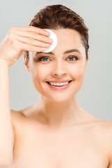 happy naked woman holding cotton pad near face isolated on grey