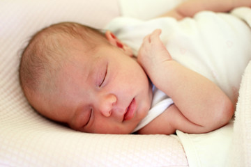 Portrait of cute newborn baby sleeping on a pink bed under beige blanket.