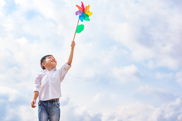 Boy holding colorful pinwheel in windy at outdoors. Children portrait and kids playing theme. - Powered by Adobe